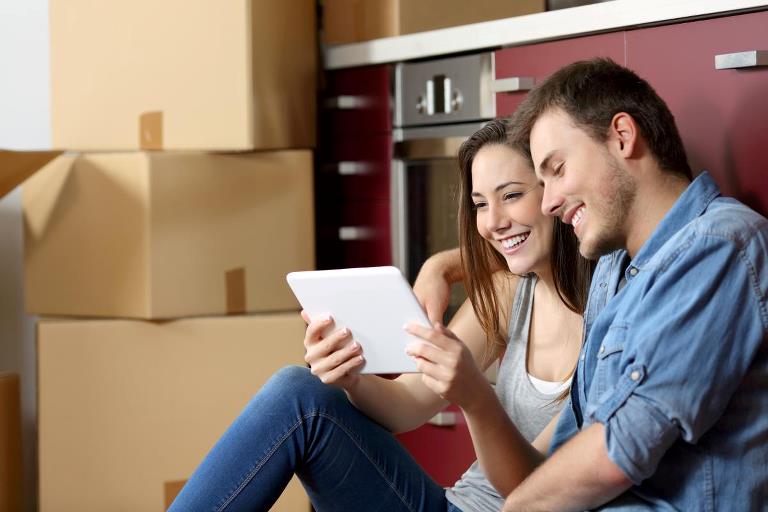 Couple looking at ipad between moving boxes